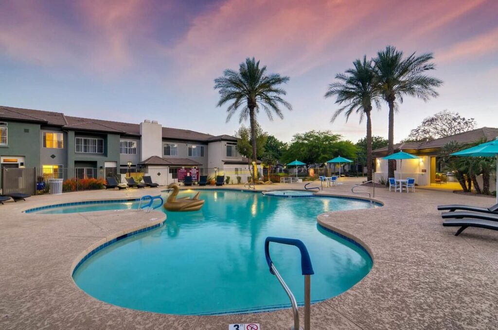 Pool with deck seating and large palm trees